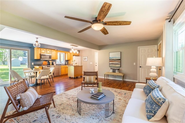 living room with dark wood-type flooring, ceiling fan, and baseboards