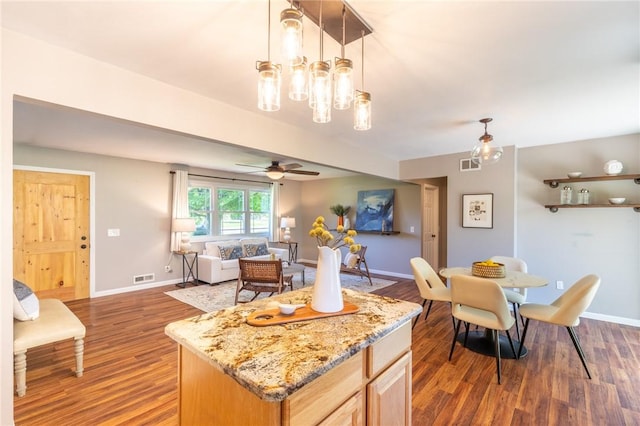 kitchen featuring ceiling fan, wood finished floors, baseboards, and light stone counters