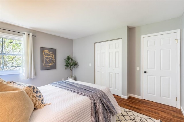 bedroom with dark wood-style flooring, a closet, and baseboards