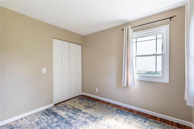 unfurnished bedroom with baseboards, wood finished floors, and a closet