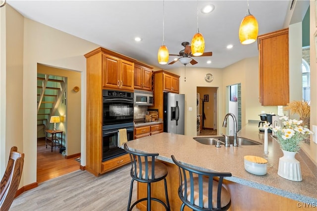 1210 Lake Rd, Oneida-Outside, NY 13421 - kitchen featuring appliances with stainless steel finishes, a sink, a peninsula, light wood-type flooring, and brown cabinetry