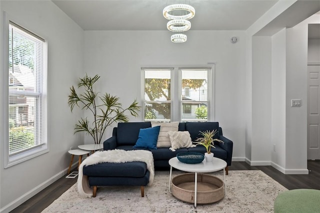 living area with plenty of natural light, dark wood finished floors, baseboards, and a chandelier