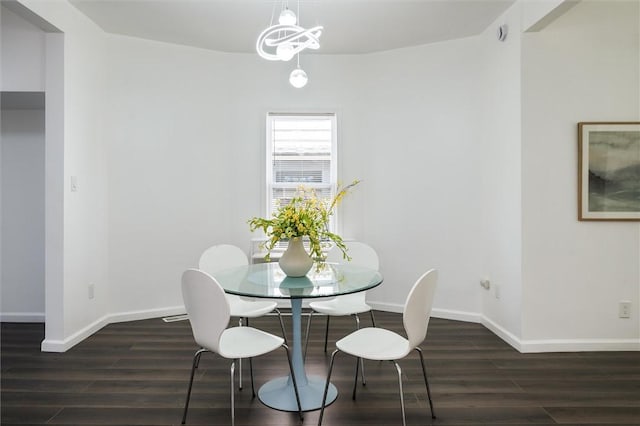 dining space featuring dark wood-type flooring, baseboards, and a chandelier