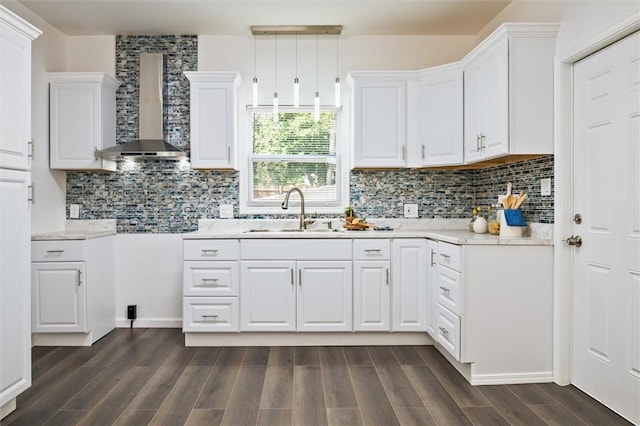 kitchen featuring wall chimney exhaust hood, a sink, white cabinets, dark wood finished floors, and decorative backsplash