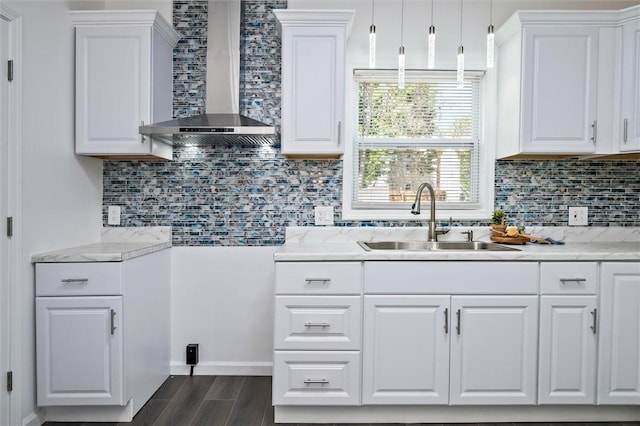 kitchen with wall chimney exhaust hood, a sink, white cabinetry, decorative backsplash, and dark wood finished floors