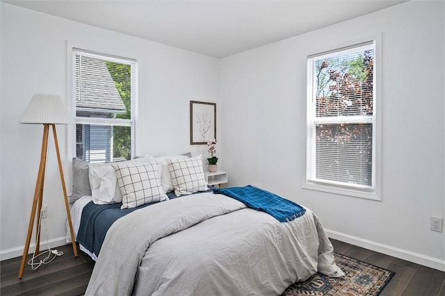 bedroom featuring multiple windows, dark wood-type flooring, and baseboards
