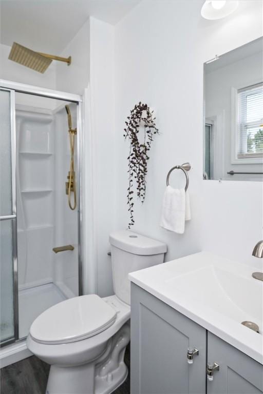 bathroom with vanity, toilet, a shower stall, and wood finished floors