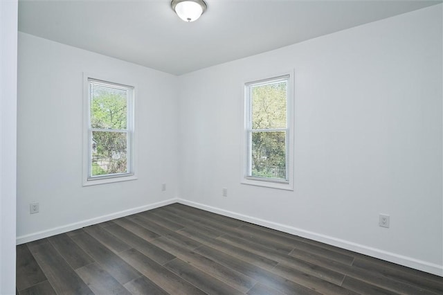 spare room featuring dark wood-type flooring and baseboards