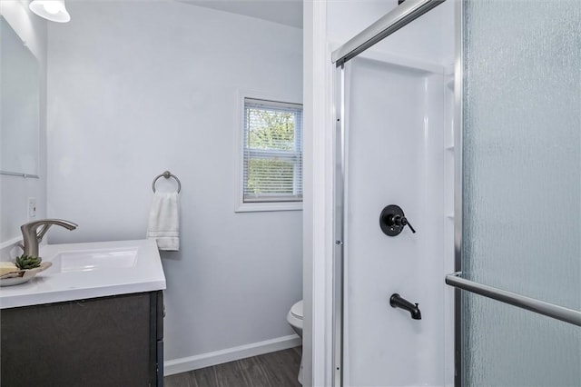 full bath featuring a stall shower, wood finished floors, toilet, vanity, and baseboards
