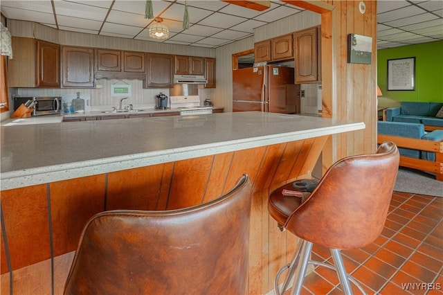 4609 E Lake Rd, Wilson, NY 14172 - kitchen with a paneled ceiling, freestanding refrigerator, white electric range, a sink, and under cabinet range hood