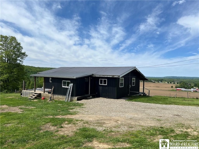 319 Ericsson Rd, Poland, NY 14747 - rear view of house with metal roof, gravel driveway, and board and batten siding