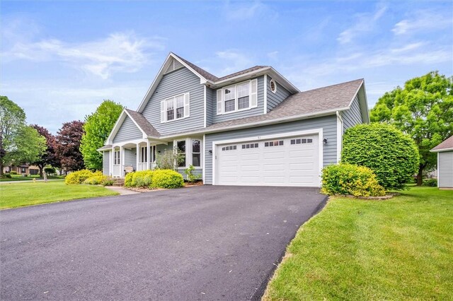 traditional-style house featuring a front lawn, driveway, covered porch, and a shingled roof
