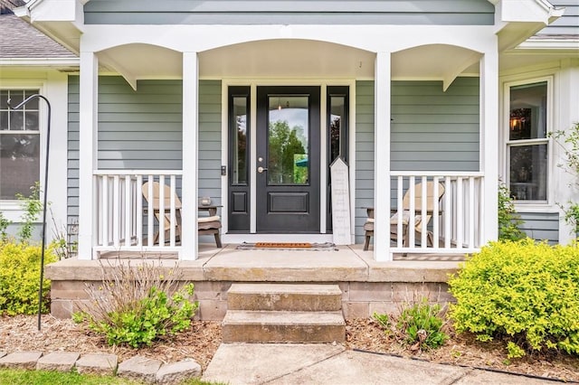 view of exterior entry featuring a porch and roof with shingles