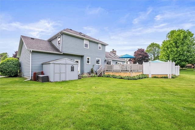 rear view of property featuring a yard, a wooden deck, and a shingled roof