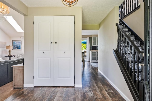 entryway with dark wood finished floors, a chandelier, baseboards, and stairway