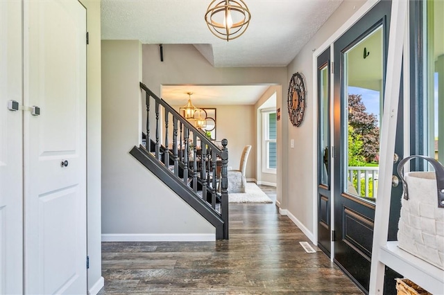 foyer entrance with a chandelier, wood finished floors, stairway, and baseboards