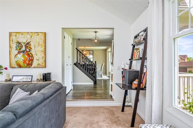 living room with stairway, carpet flooring, vaulted ceiling, a chandelier, and baseboards