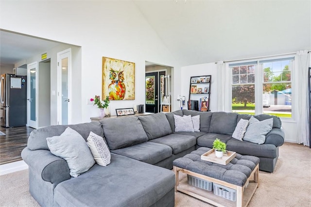 carpeted living area with plenty of natural light, high vaulted ceiling, and baseboards