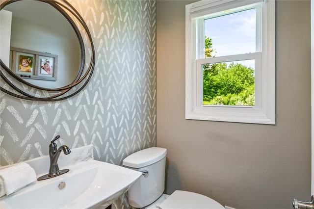 bathroom featuring wallpapered walls, a sink, and toilet