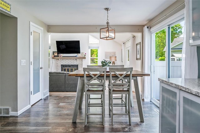 dining area featuring dark wood-type flooring, a fireplace, baseboards, and wine cooler
