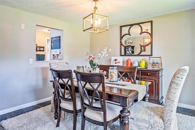 dining room with a chandelier, baseboards, and wood finished floors