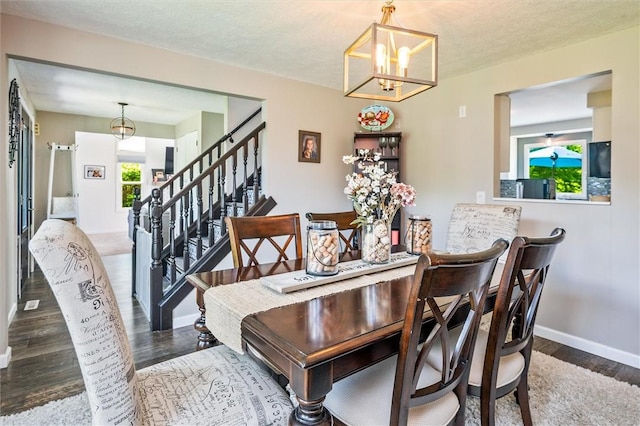 dining room featuring a chandelier, wood finished floors, stairs, and baseboards