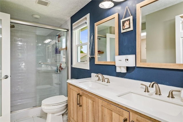 full bath featuring a stall shower, toilet, a textured ceiling, and double vanity