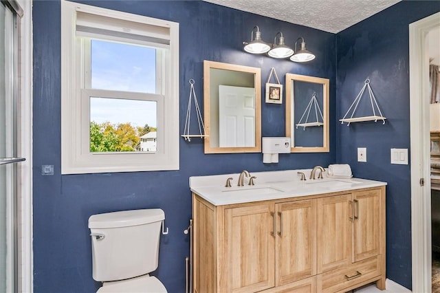 full bath featuring toilet, double vanity, and a textured ceiling