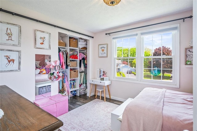 bedroom with wood finished floors, a closet, baseboards, and a textured ceiling