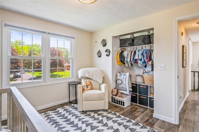 bedroom featuring wood finished floors, baseboards, a textured ceiling, and a closet
