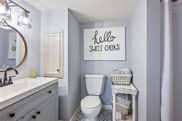 bathroom with toilet, baseboards, and vanity