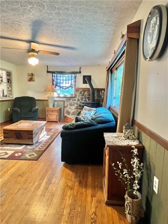 4600 College Ave, Corning, NY 14830 - living area with a wainscoted wall, healthy amount of natural light, wood finished floors, a wood stove, and a textured ceiling