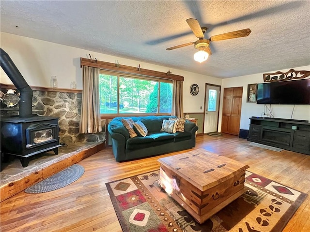 4600 College Ave, Corning, NY 14830 - living room featuring hardwood / wood-style flooring, a textured ceiling, a ceiling fan, and a wood stove