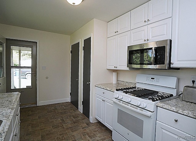 458 Kenwood Dr, Lewiston, NY 14092 - kitchen with stainless steel microwave, white gas range, stone finish floors, baseboards, and white cabinetry
