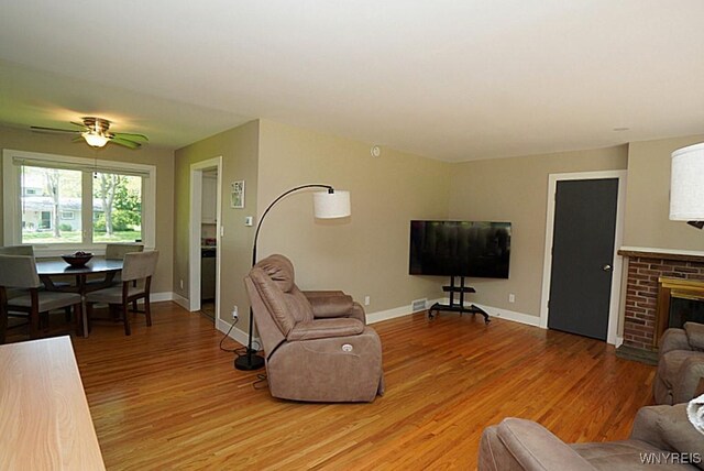 458 Kenwood Dr, Lewiston, NY 14092 - living area featuring light wood finished floors, baseboards, a ceiling fan, and a fireplace