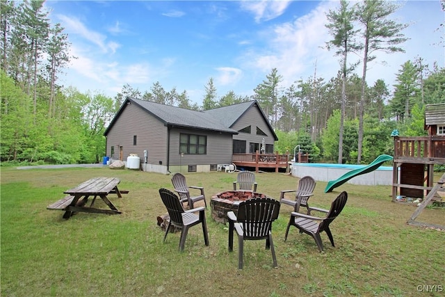 7030 Peckham Rd, Watson, NY 13367 - rear view of property featuring an outdoor fire pit, a wooden deck, a yard, and a playground
