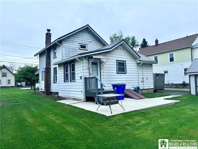 108 S Main St, Evans, NY 14006 - back of house featuring a lawn, a chimney, and a patio