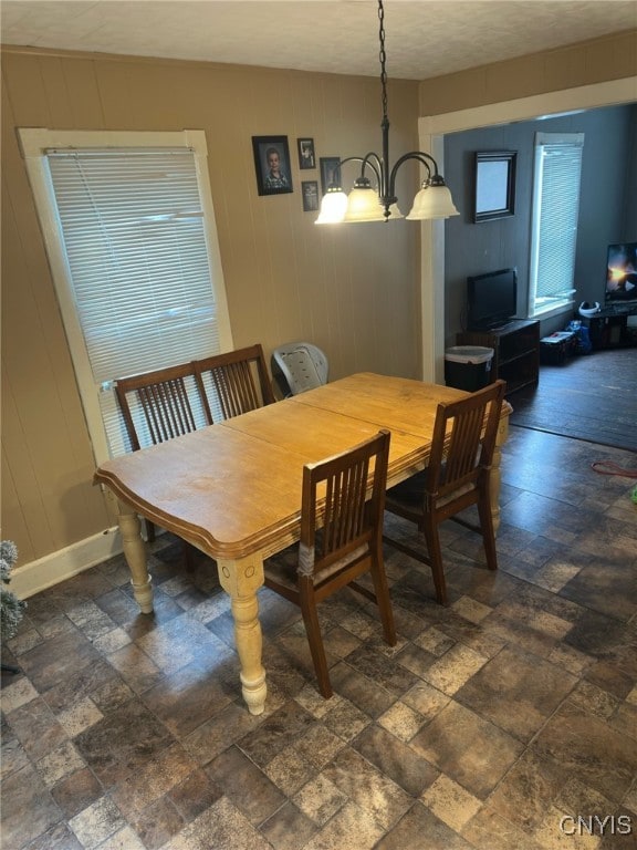 70 Prospect Ave, German Flatts, NY 13357 - dining space with a chandelier, stone finish floors, healthy amount of natural light, and wooden walls