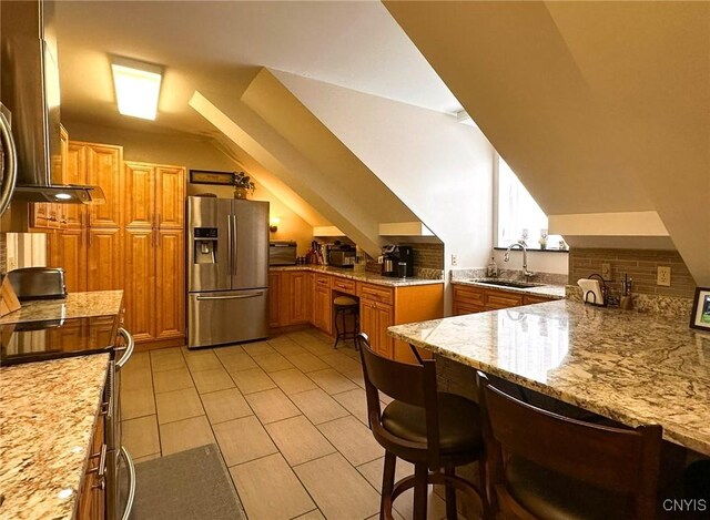 10 Foery Dr Unit 404, Utica, NY 13501 - kitchen with stainless steel fridge, a sink, brown cabinetry, lofted ceiling, and a breakfast bar area