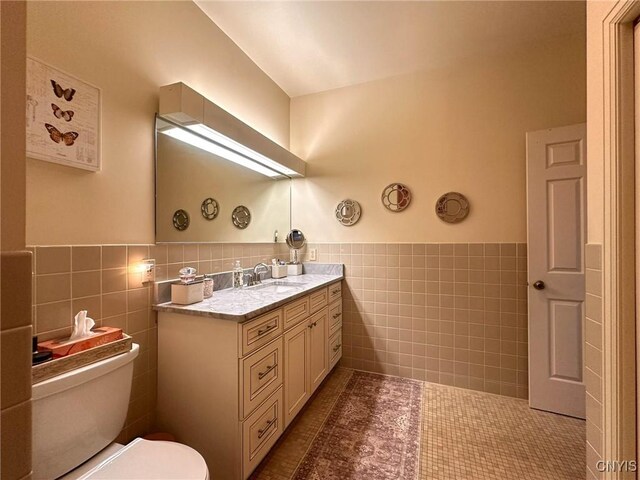 10 Foery Dr Unit 404, Utica, NY 13501 - bathroom featuring tile walls, toilet, a wainscoted wall, vanity, and tile patterned flooring