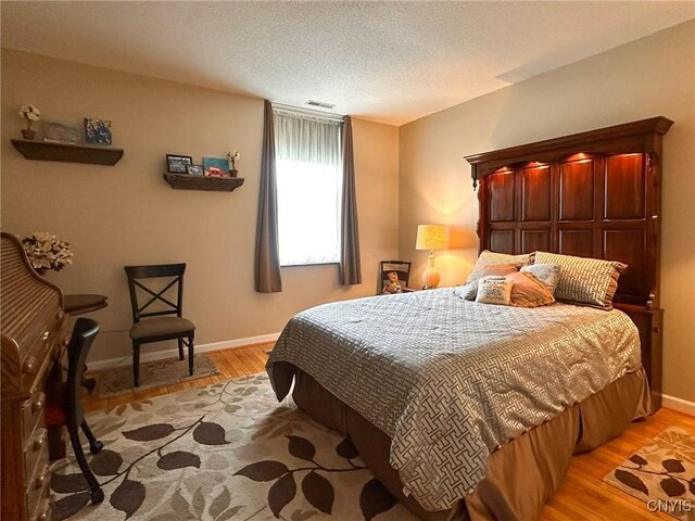10 Foery Dr Unit 404, Utica, NY 13501 - bedroom featuring light wood-type flooring, baseboards, and a textured ceiling