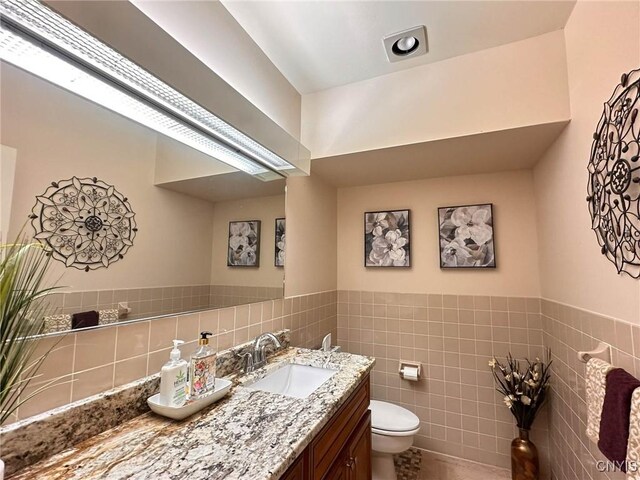 10 Foery Dr Unit 404, Utica, NY 13501 - half bath featuring toilet, tile walls, vanity, and wainscoting