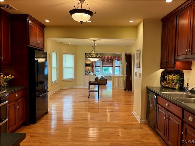 kitchen with black appliances, a sink, dark countertops, light wood finished floors, and recessed lighting
