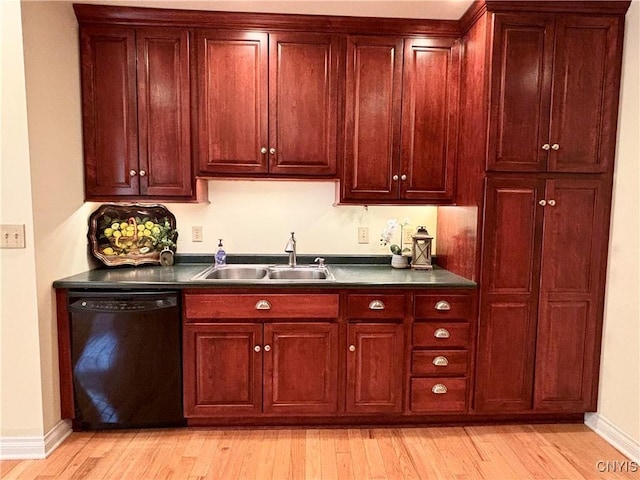 kitchen featuring black dishwasher, a sink, dark countertops, and light wood finished floors