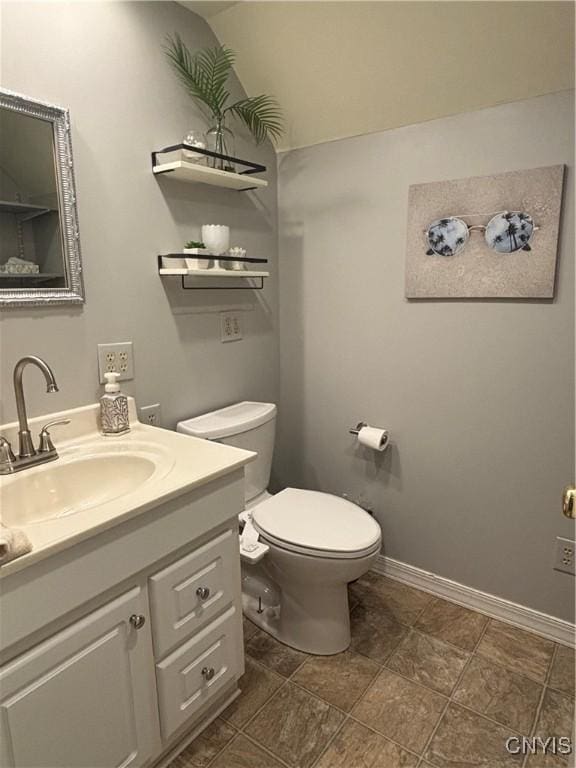 half bathroom with vanity, toilet, and baseboards