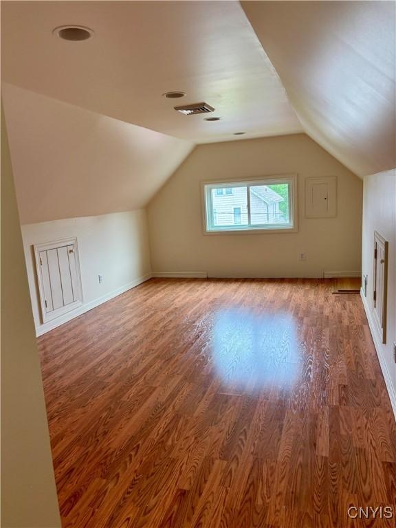 bonus room featuring wood finished floors, vaulted ceiling, and baseboards