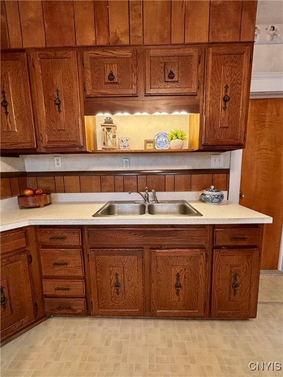 kitchen with a sink, brown cabinetry, and light countertops