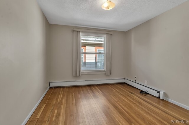 1681 Amherst St, Buffalo, NY 14214 - unfurnished room with hardwood / wood-style floors, baseboards, a textured ceiling, a baseboard heating unit, and a baseboard radiator