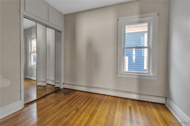1681 Amherst St, Buffalo, NY 14214 - unfurnished bedroom featuring a baseboard radiator, light wood-style flooring, and a closet