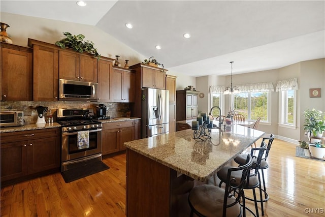 146 Edwards Falls Ln, Manlius, NY 13104 - kitchen with stainless steel appliances, a breakfast bar, decorative backsplash, light wood-type flooring, and lofted ceiling